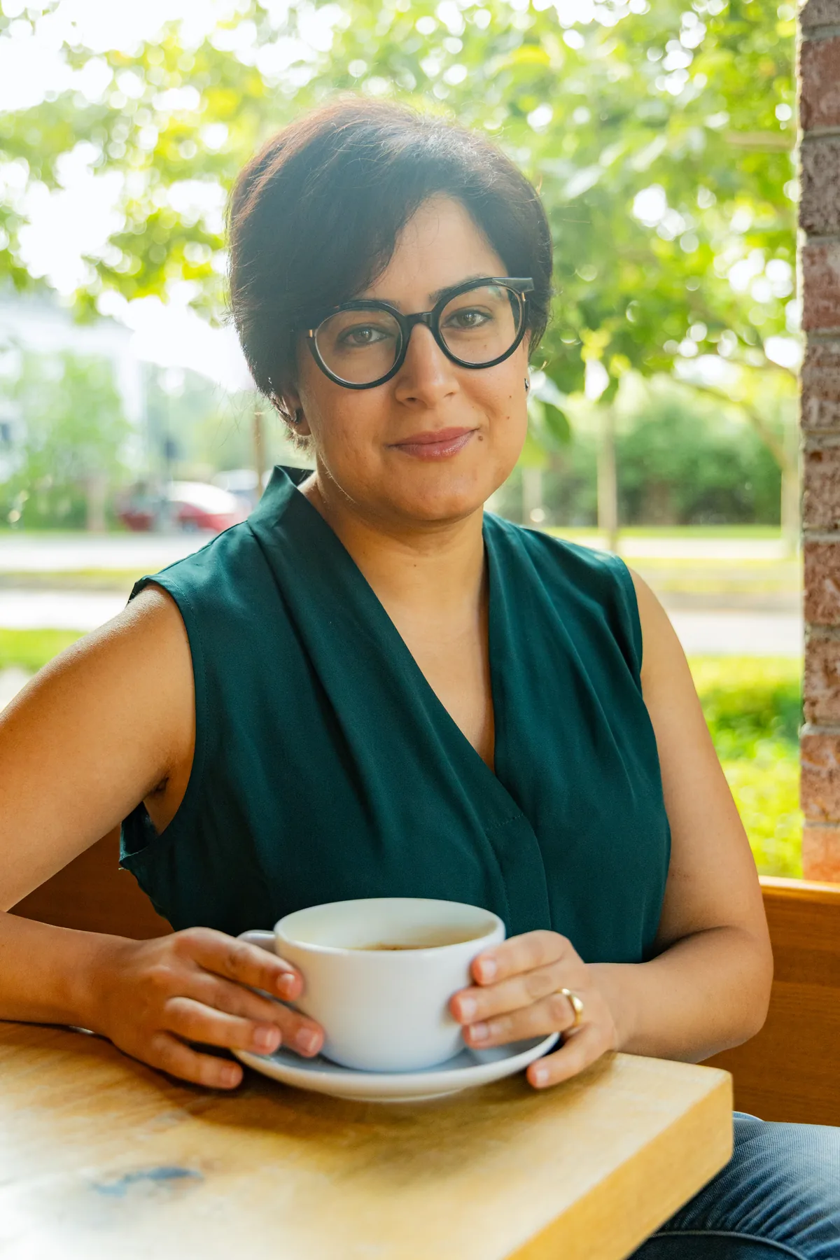 Dr. Mira Massoud sitting at a cafe table with a cup of coffee