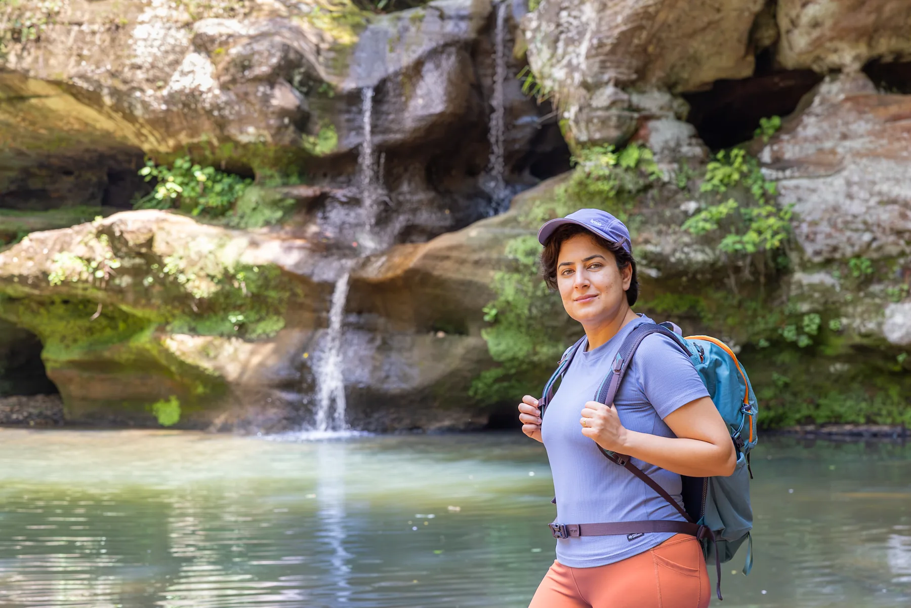 Dr. Mira Massoud hiking past a waterfall in Hocking Hills, Ohio